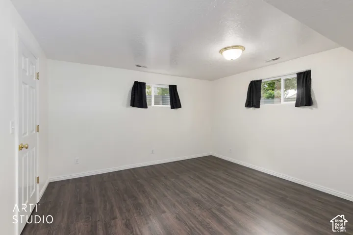 White interior walls, wood-finish flooring, two windows, and a flush-mount ceiling light fixture