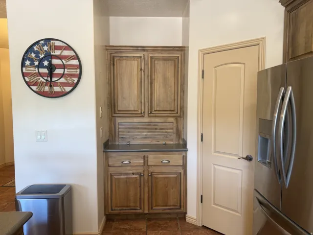 Built-in wood-finish cabinetry with a countertop surface, stainless steel refrigerator, and paneled interior door