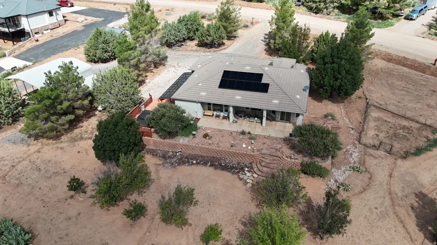 Tile roof with integrated solar panels, covered patio, terraced landscaping with stone steps, and a fenced area