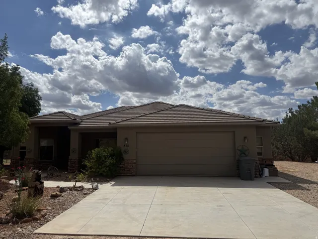 Single-story residence featuring a tile roof, an integrated two-car garage, and a concrete driveway