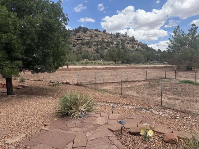 Expansive outdoor area featuring mature trees, a natural rock hillside backdrop, and a stone patio