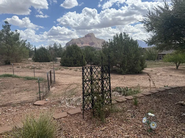 Expansive outdoor space featuring a mountain backdrop, mature trees, and a decorative garden trellis