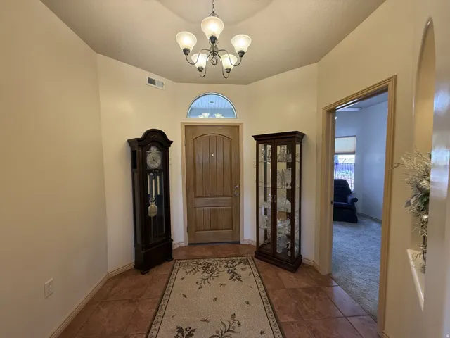 Arched entry door with upper transom window and a multi-light chandelier
