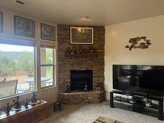 Stone-clad corner fireplace with a built-in mantel, recessed gas insert, and an elevated hearth