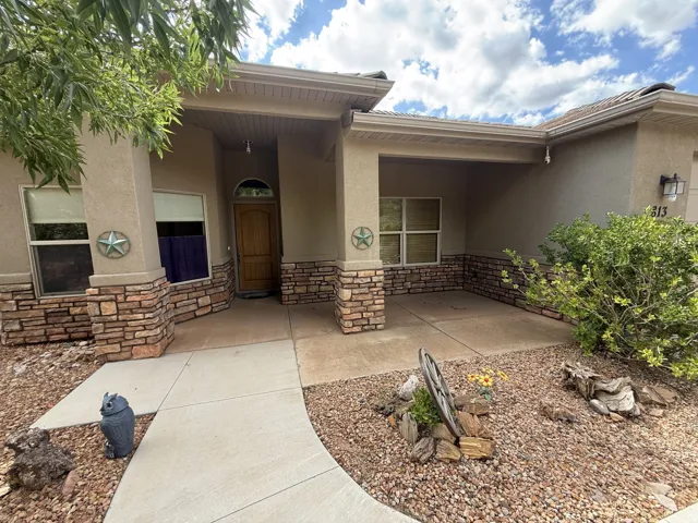 Stucco exterior with stone veneer accents, covered entry, curved concrete walkway, and gravel landscaping