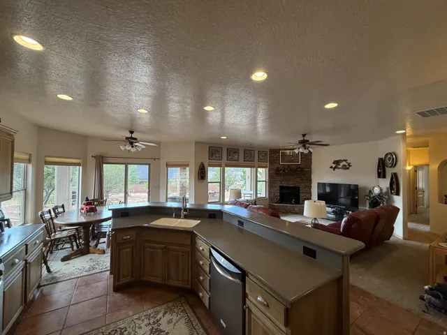 Open-concept kitchen with recessed lighting, stone-finish countertops, and wood cabinetry