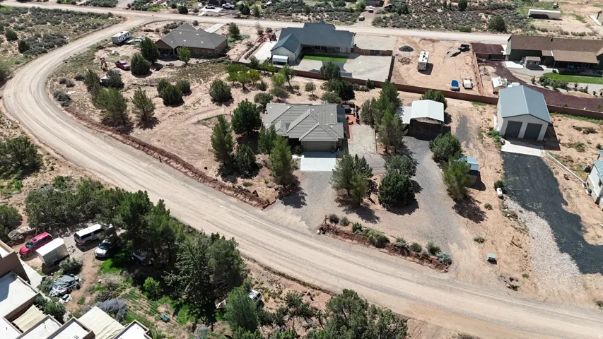 Single-story residence featuring an attached garage, gravel driveway, and surrounding mature trees