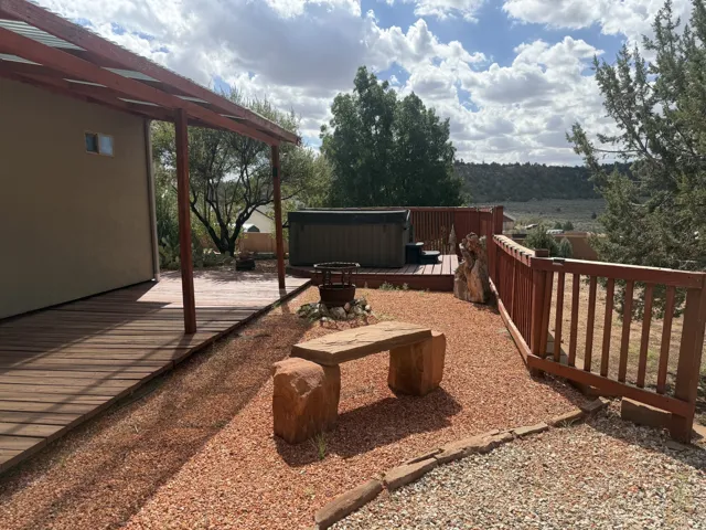 Expansive wooden deck with a covered portion, featuring a built-in hot tub