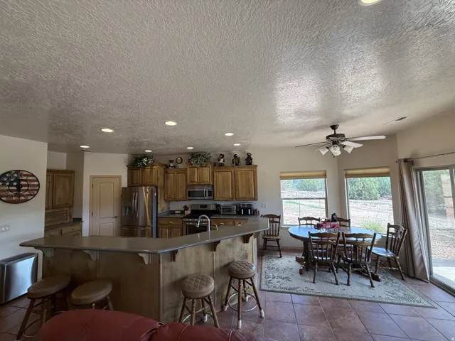 Kitchen featuring wood cabinetry, stainless steel appliances, a breakfast bar with countertop seating, and recessed lighting