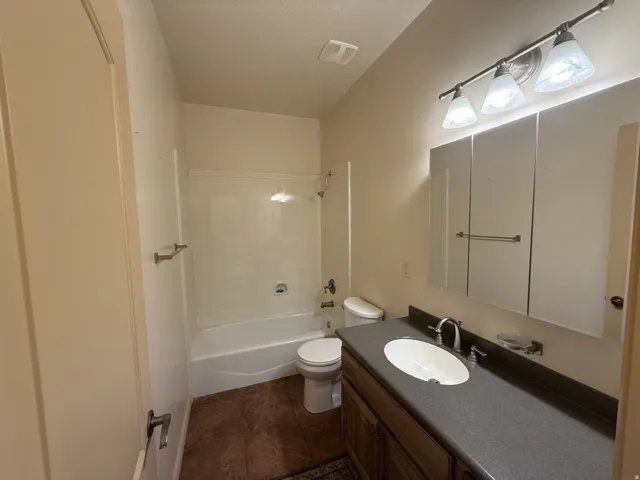 Bathroom featuring a vanity with an oval basin sink, a three-light fixture, a medicine cabinet, and a shower-tub combination
