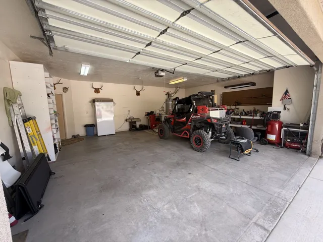 Spacious garage with concrete flooring, overhead fluorescent lighting, and an automatic garage door