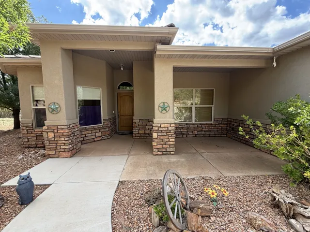 Stucco exterior with stone veneer accents, covered entry, wood-finish front door with arched transom, and concrete walkway