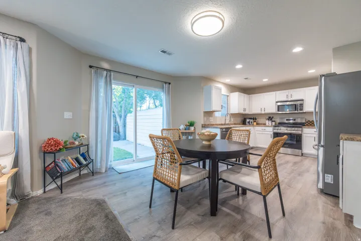 Kitchen with white cabinetry, newer stainless steel appliances, LVP flooring, and sliding door to backyard