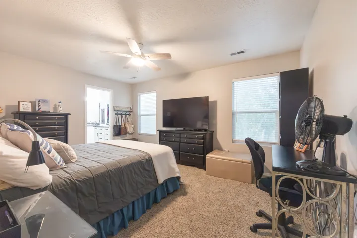 Spacious primary bedroom with ceiling fan with integrated lighting, and 2 windows with views