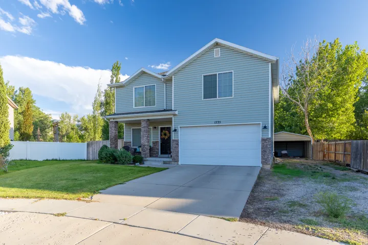 Two-story residence with a covered front porch featuring stone accents, an attached 2-car garage, RV parking, & 2-car carport