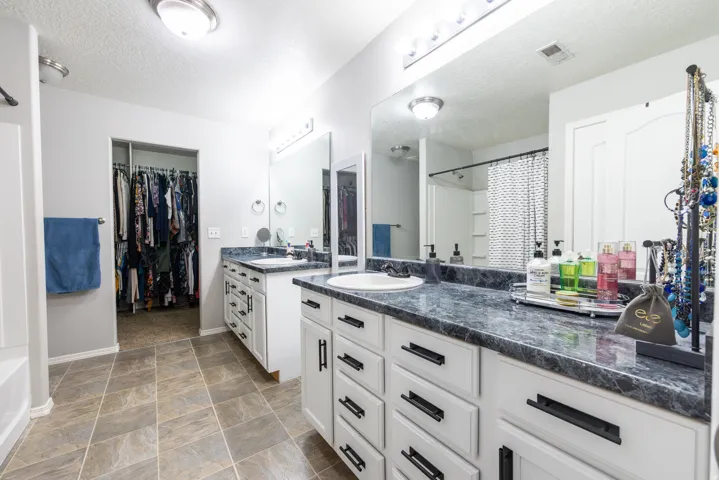 Primary suite with dual vanity and lots of cabinetry set against a full-width mirror