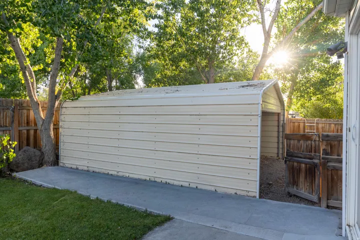 Metal 2-car carport/storage, concrete pad, and wood fencing