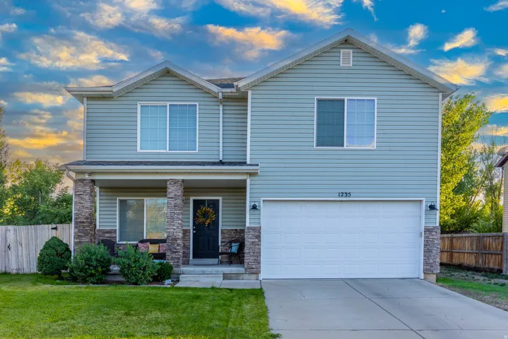 Beautiful home with stone-clad porch columns, covered front porch, attached garage, and a gorgeous setting