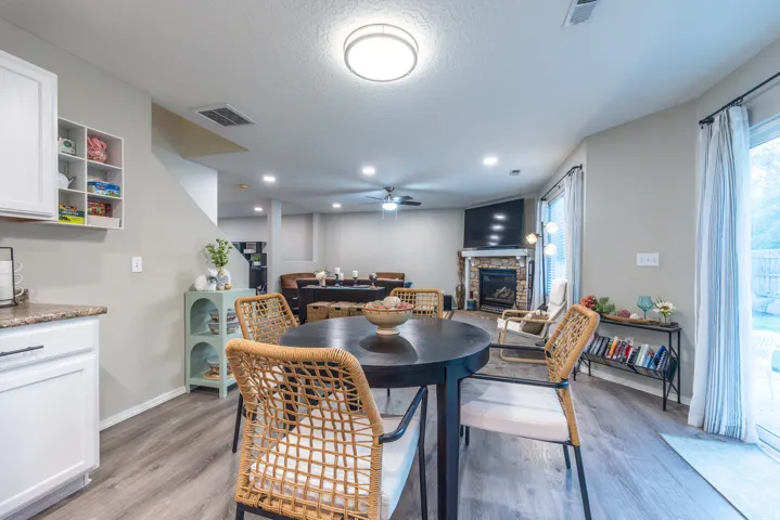Open great room with LVP flooring, recessed lighting, and a cozy stone fireplace