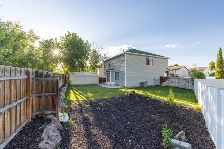 Backyard featuring a fully fenced perimeter, garden area, and carport/shed for additional storage