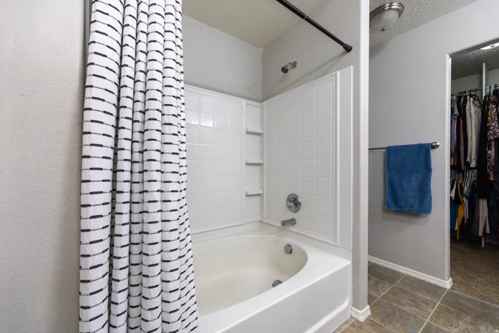 Primary suite tub/shower combination with white surround and built-in shelving