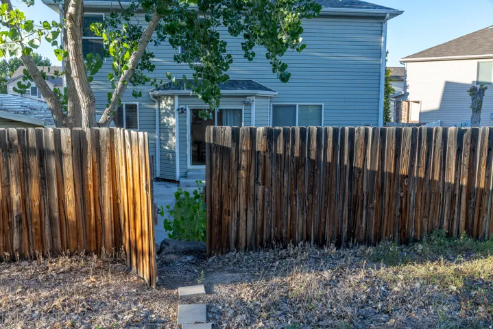 Private wood fencing with a gate and stone pavers