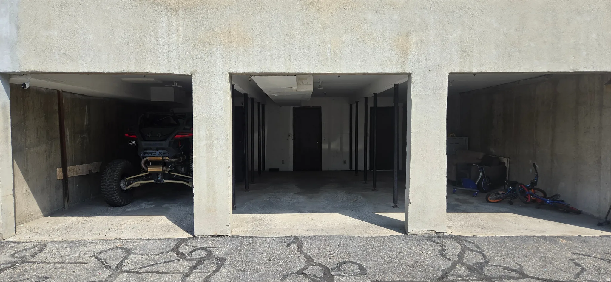Three garage bays with concrete flooring and textured concrete walls