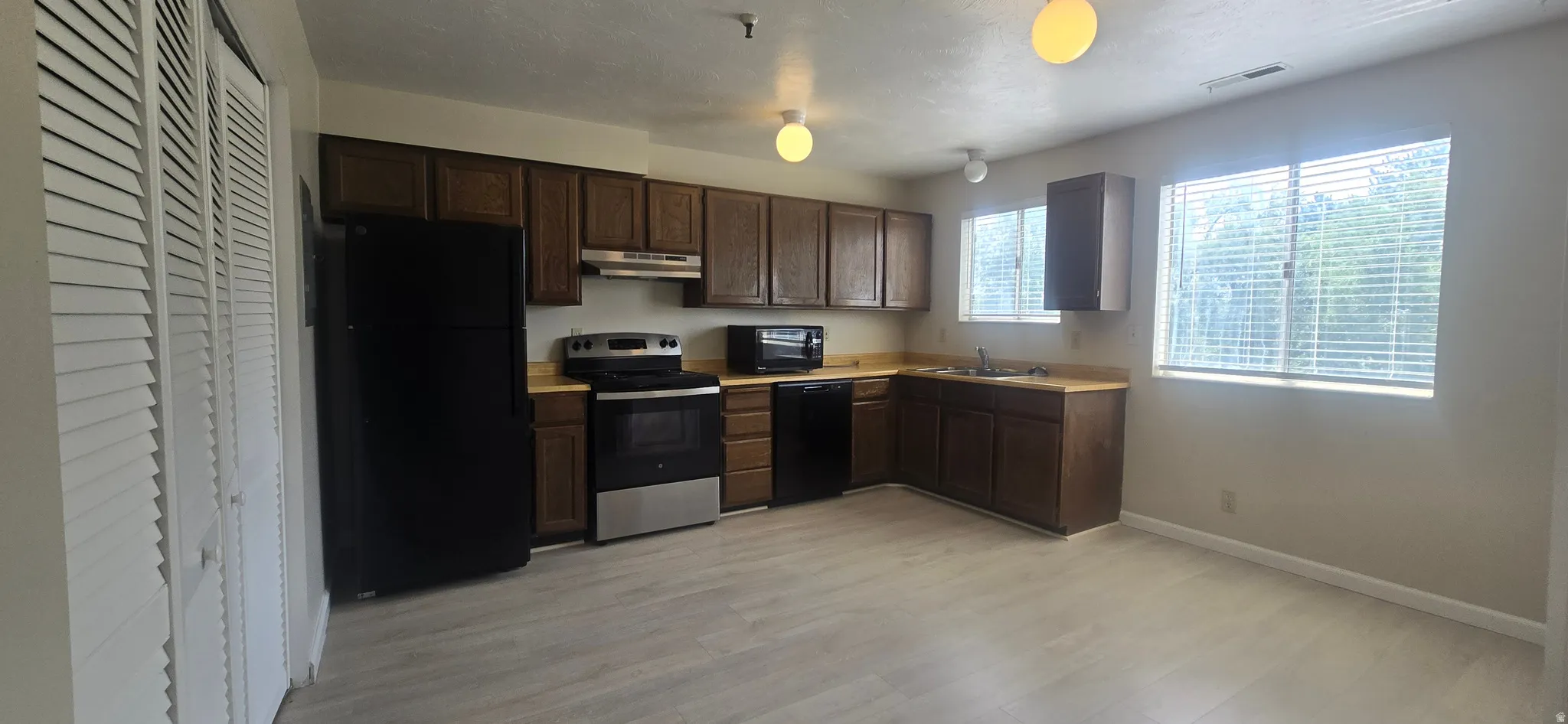 Kitchen featuring wood-finish cabinetry, stainless steel range, and wood-finish flooring