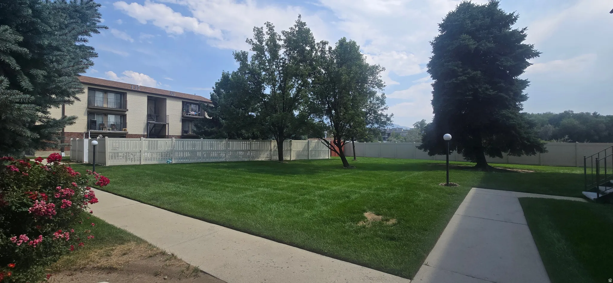 Expansive green lawn area with mature trees and perimeter fencing