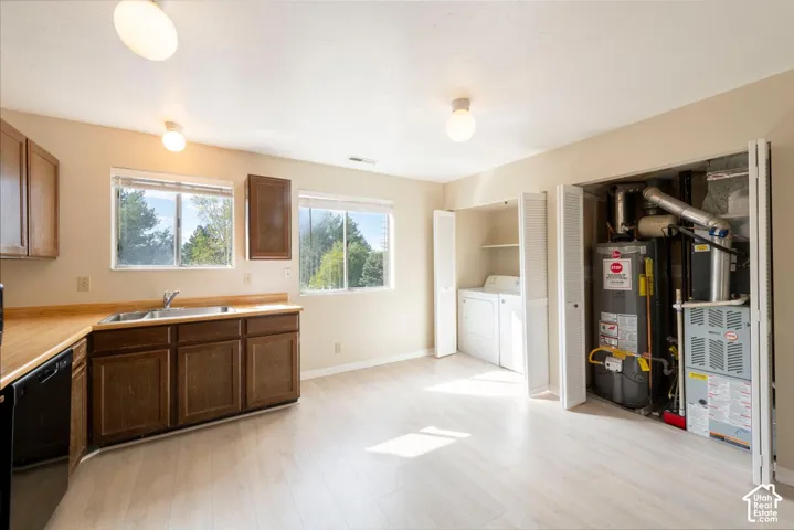 Kitchenette with wood-finish flooring, two windows, wood cabinetry, and a double basin stainless steel sink