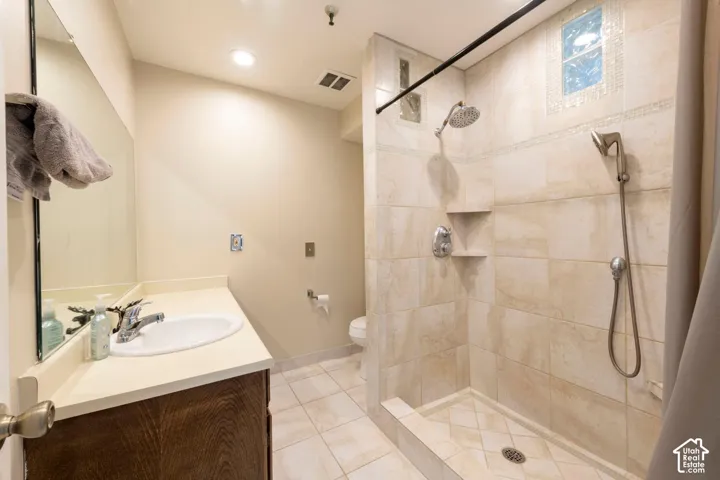 Floor-level shower with dual shower heads, integrated shelf, and tiled walls