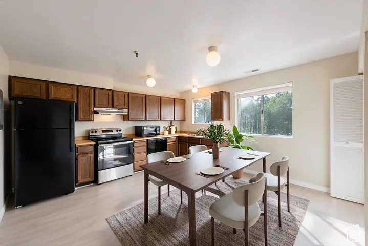 Wood-finish flooring, wood cabinetry, stainless steel range, built-in microwave, and large windows