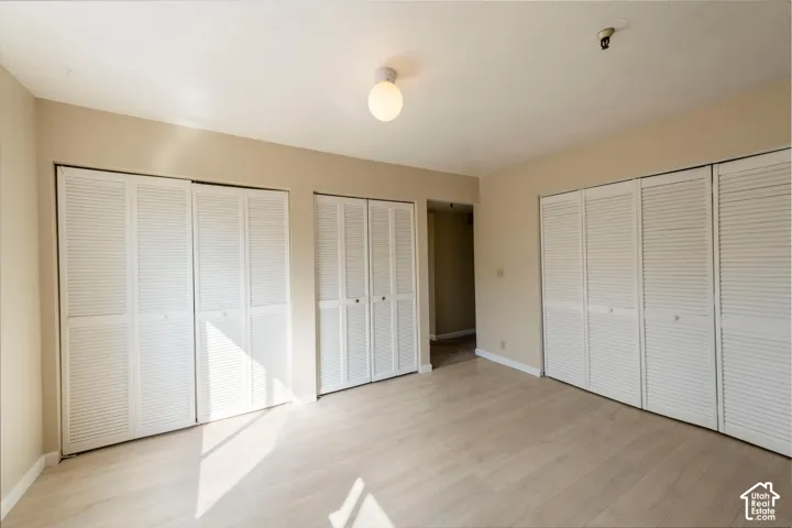 Wood-finish flooring, multiple louvered bifold closet doors, and recessed lighting