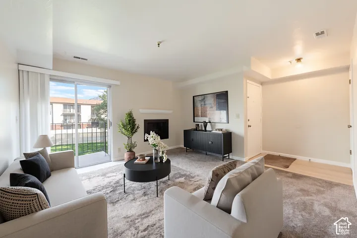 Living area with soft carpet flooring, a built-in fireplace, and a sliding glass door leading to a private balcony
