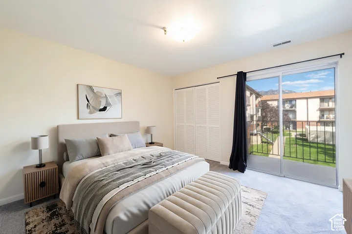 Sliding glass door leading to an outdoor balcony, white bi-fold closet doors, wall-to-wall carpeting, light-colored walls, and a ceiling-mounted light fixture