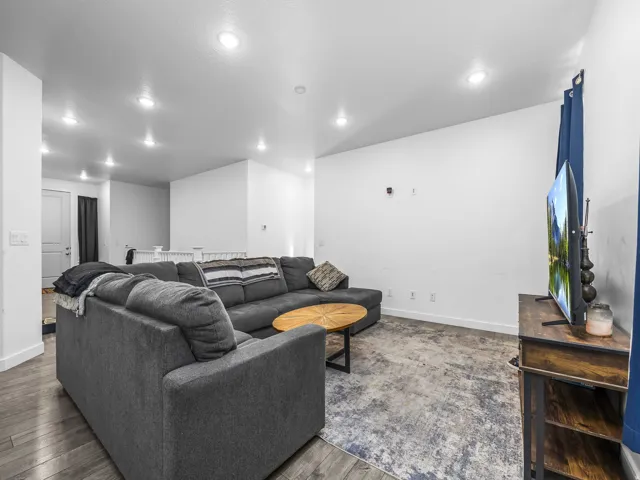 Recessed lighting illuminates this room featuring wood-finish flooring and white painted walls