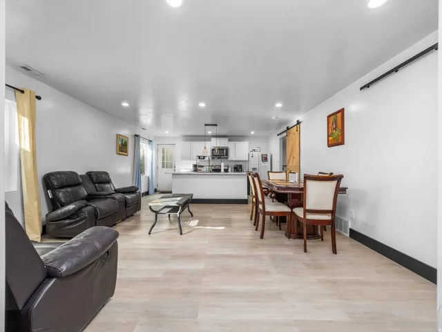 Recessed lighting, wood-finish flooring, white walls, and a barn door entry