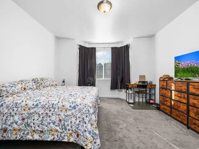 Carpeted room featuring a bay window with dark drapes, white walls, and a ceiling-mounted light fixture