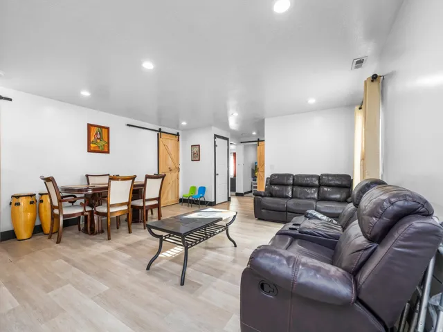 Recessed lighting, light wood-finish flooring, white walls, and a barn door