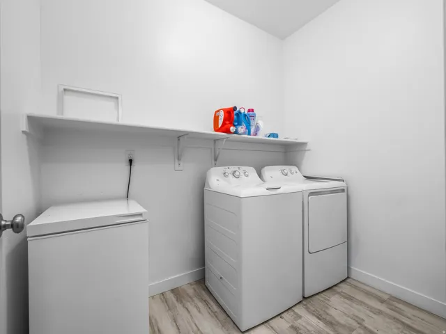 Dedicated laundry area featuring a wall-mounted shelf and wood-finish flooring