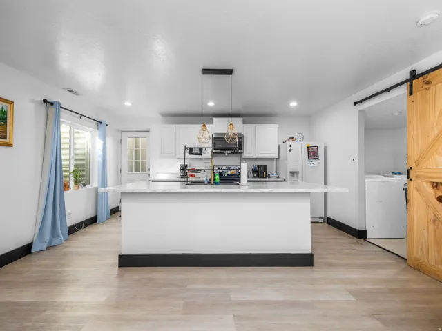 Central kitchen island with a stone-finish countertop, recessed lighting, and wood-finish flooring