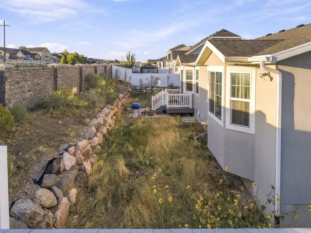Exterior featuring a bay window, stucco siding, a white deck with railings, and a stone retaining wall