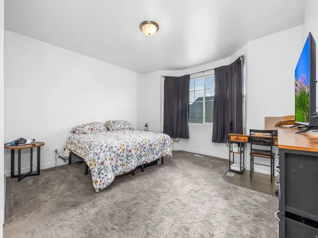 Bay window with dark curtains, light-colored walls, and gray carpeting