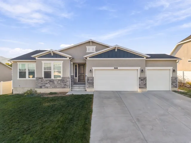 Stucco exterior with stone accents, covered entry, and a two-car garage