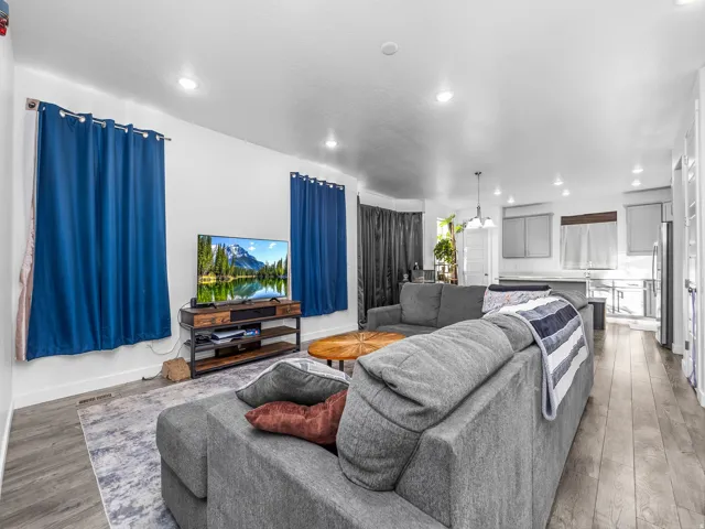 Open-concept living space with wood-finish flooring, recessed lighting, and a kitchen featuring light-toned cabinetry