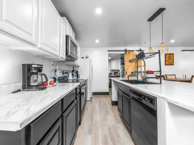 Contemporary kitchen featuring white upper cabinetry, dark lower cabinetry, and light-toned wood-finish flooring
