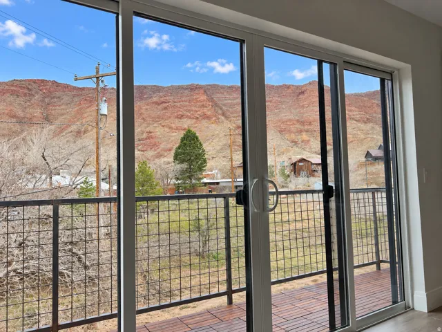 Sliding glass doors opening to a private balcony with metal grid railing and wood-finish decking