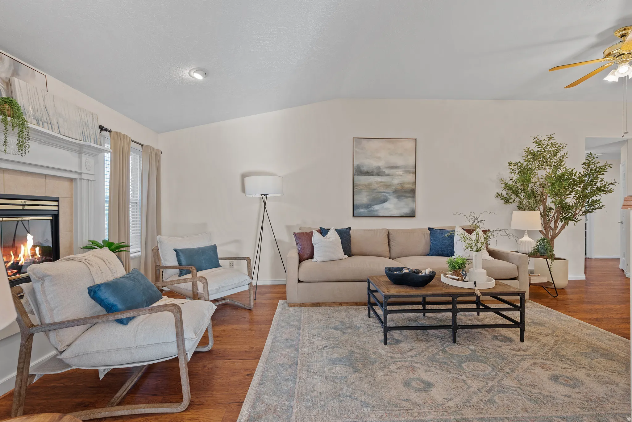Spacious living area featuring wood-finish flooring, a fireplace with a white mantel, and recessed ceiling lighting
