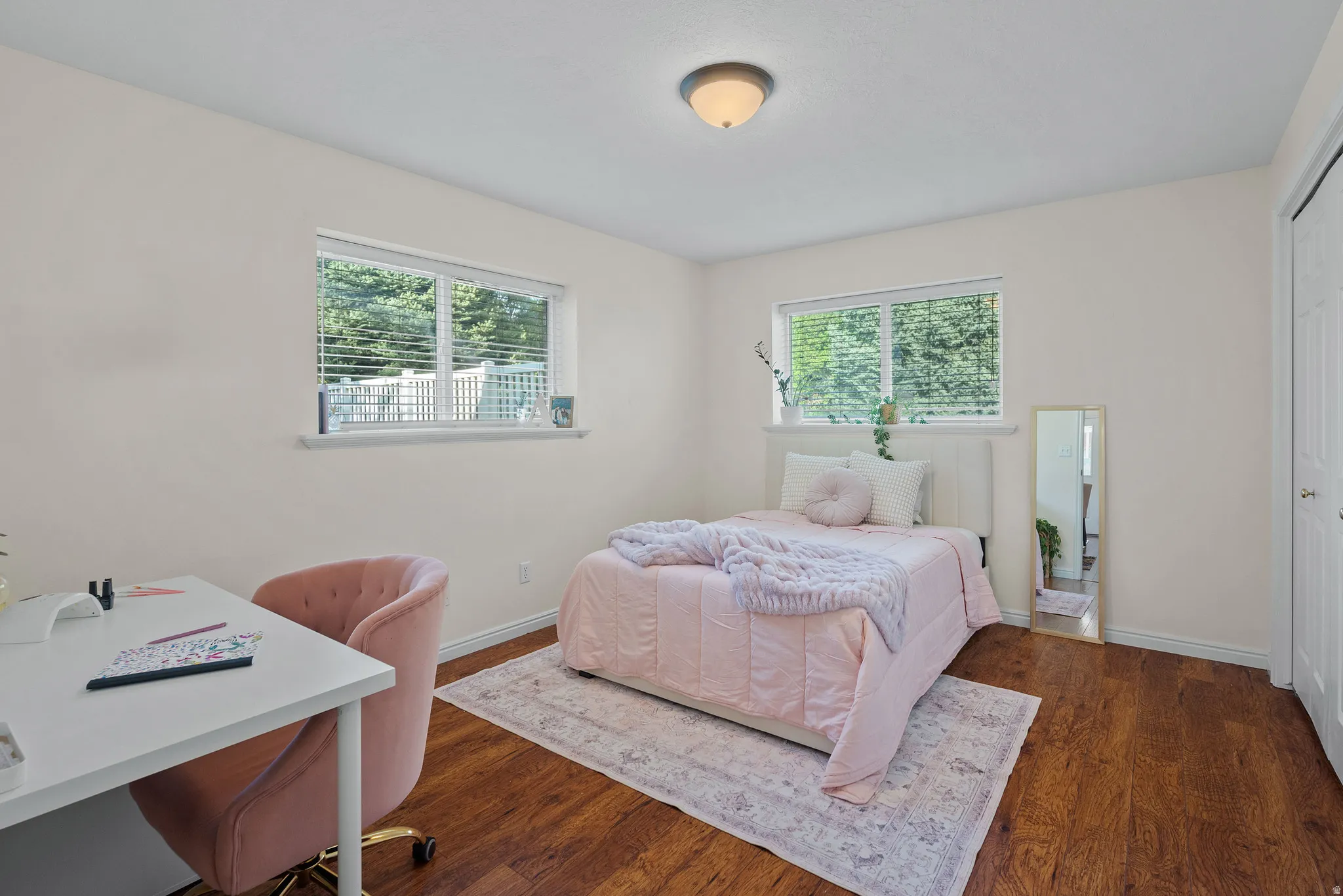 Hardwood-style flooring, dual windows with blinds, built-in closet with bi-fold doors, and a ceiling-mounted light fixture