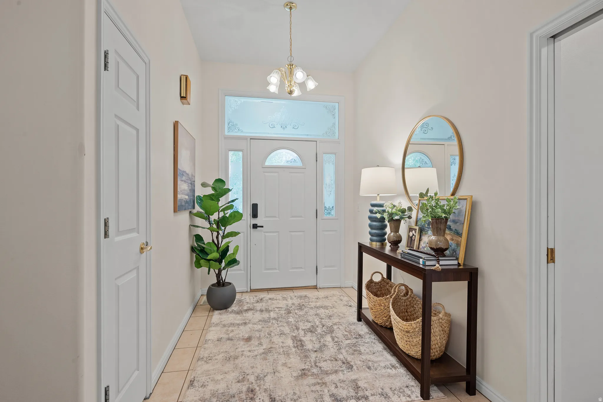 Tile flooring in the entryway, complemented by a white paneled door and transom window with decorative glass